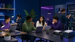 An illustration of a diverse group of beginners in a modern workspace, studying on laptops, building a home lab, and discussing IT certifications, all set against a deep navy background.