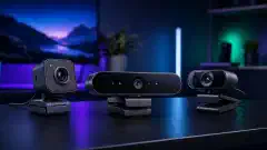 An illustration of various webcams on a modern desk, including the Logitech BRIO, StreamCam, and a traditional webcam, set against a blurred home office background.